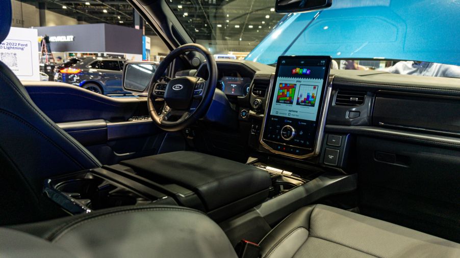 The front interior of a 2022 Ford F-150 Lightning with its folding table deployed at the 2021 Chicago Auto Show