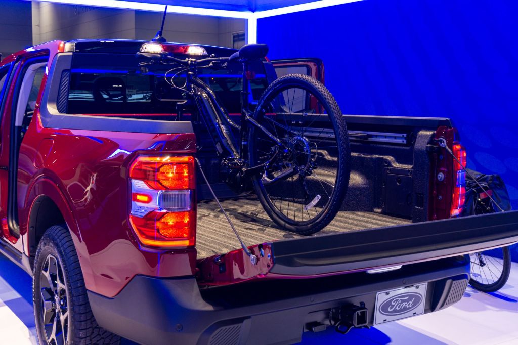 The bed of a red 2022 Ford Maverick Lariat with a black mountain bike mounted inside