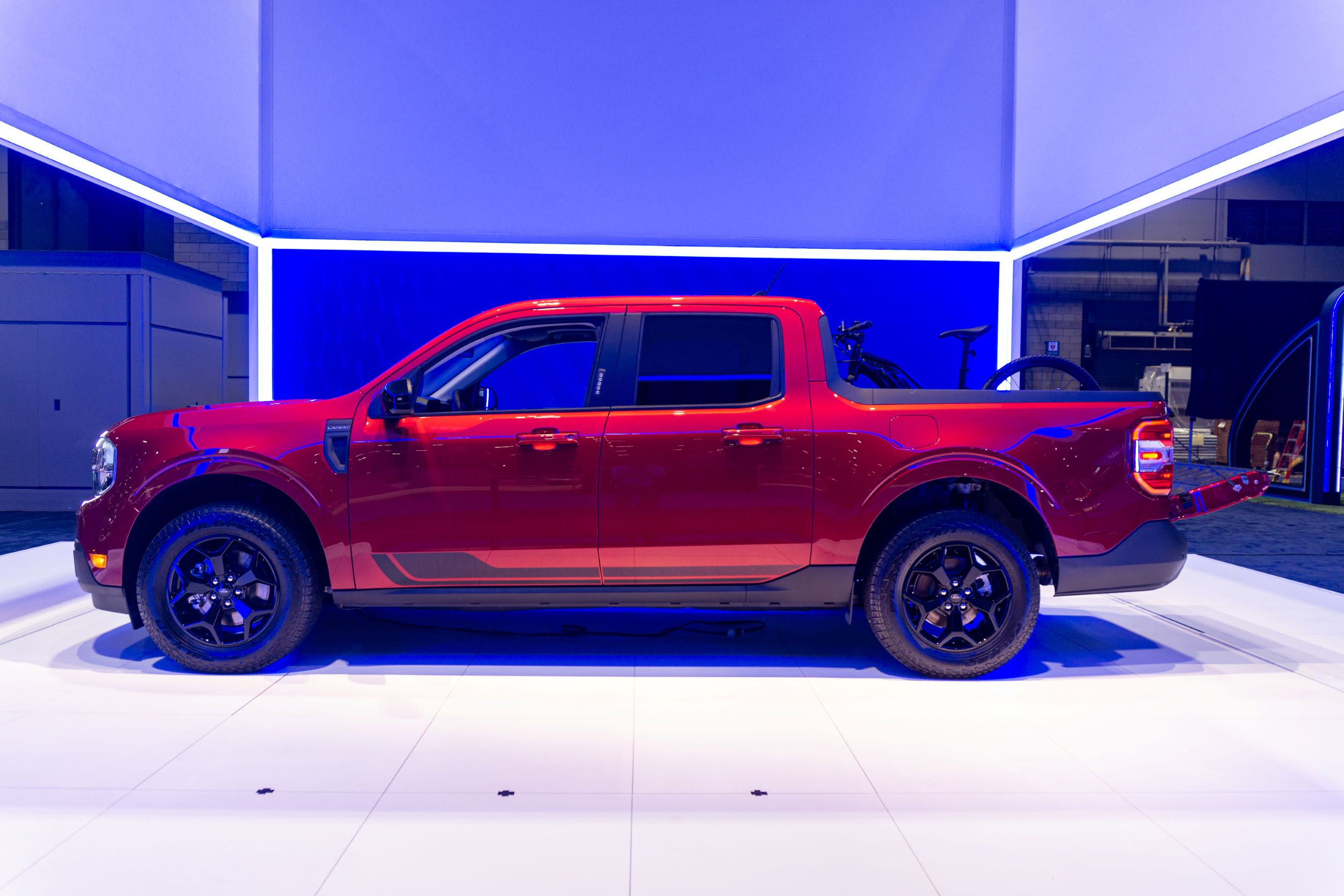 The side view of a red 2022 Ford Maverick Lariat with a bike in the bed at the 2021 Chicago Auto Show