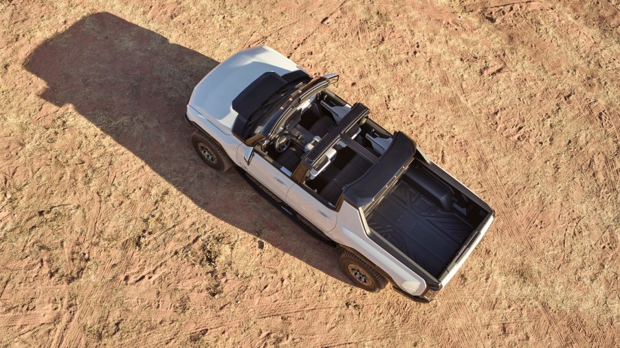 An overhead view of the 2022 GMC Hummer EV, parked on an expanse of beige dirt, with its roof removed