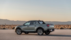 A silver 2022 Hyundai Santa Cruz parked on asphalt in a desert with mountains in the distance
