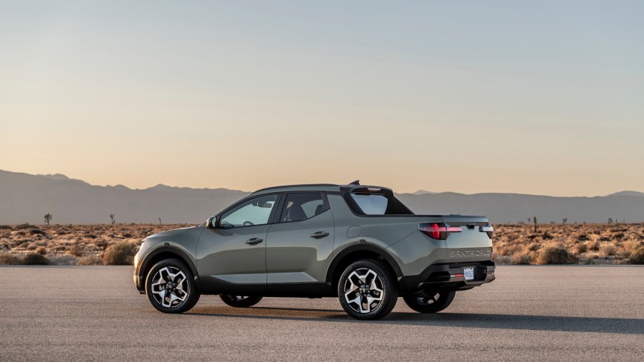 A silver 2022 Hyundai Santa Cruz parked on asphalt in a desert with mountains in the distance
