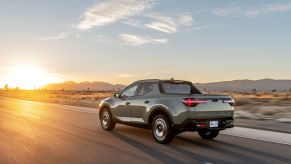 The 2022 Hyundai Santa Cruz pickup truck driving down a country highway as the sun rises