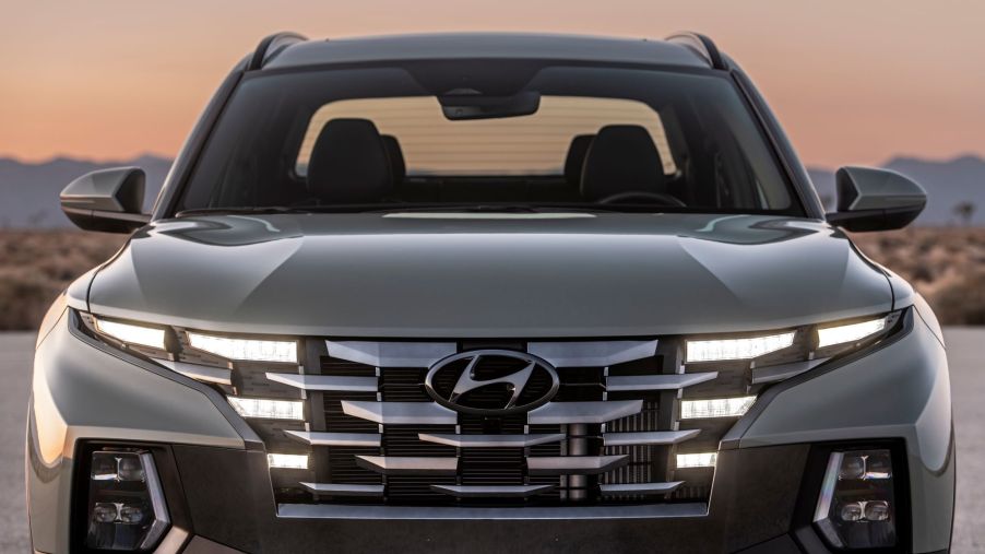 A front exterior shot of the 2022 Hyundai Santa Cruz with its headlights and grille lit up