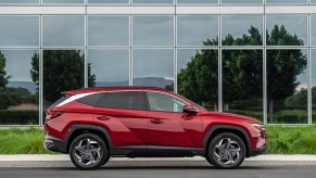 A cherry-red metallic 2022 Hyundai Tucson parked on the street outside a glass building