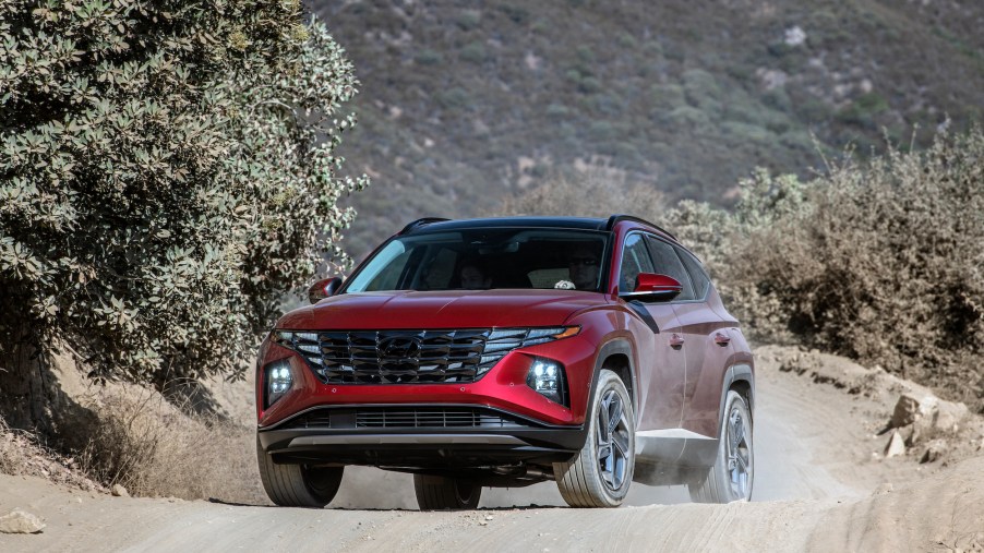 A dark-red metallic 2022 Hyundai Tucson compact SUV parked on a dusty mountain road