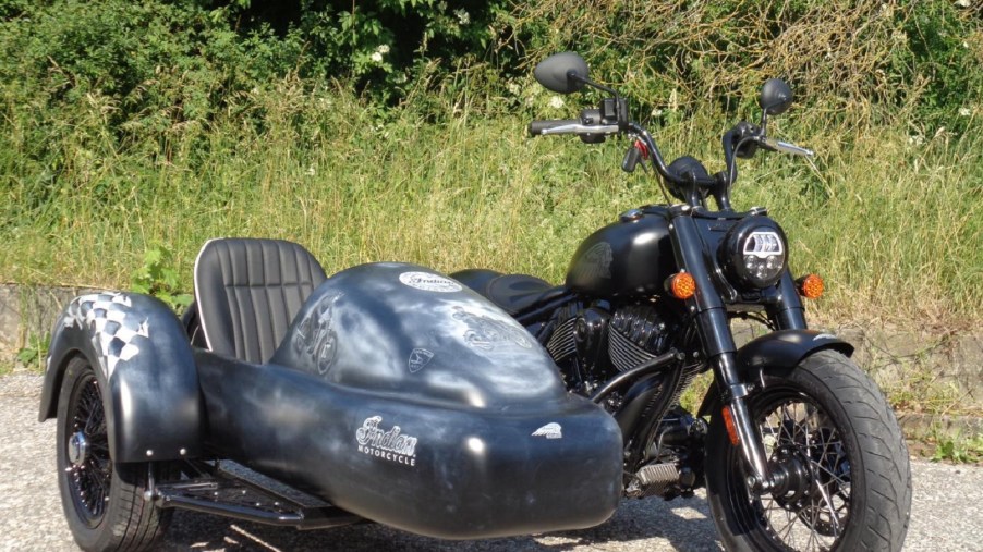 A black 2022 Indian Chief Bobber with Iwan Bikes' BellaVista sidecar parked by the side of the road