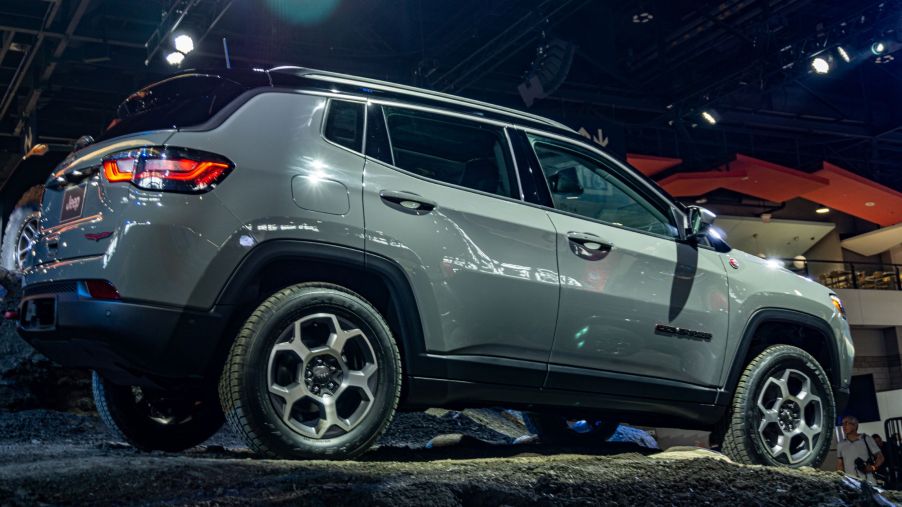 The side 3/4 view of a gray 2022 Jeep Compass Trailhawk on a simulated gravel rise