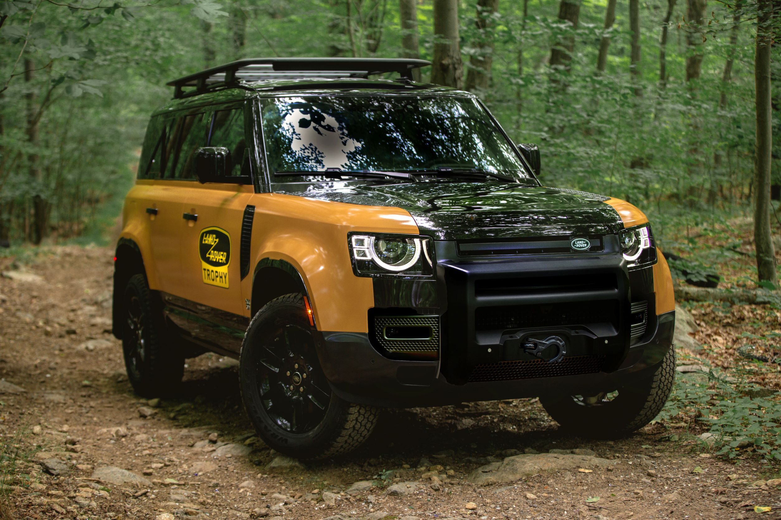 The yellow-and-black 2022 Land Rover Defender Trophy Edition with optional winch in a forest