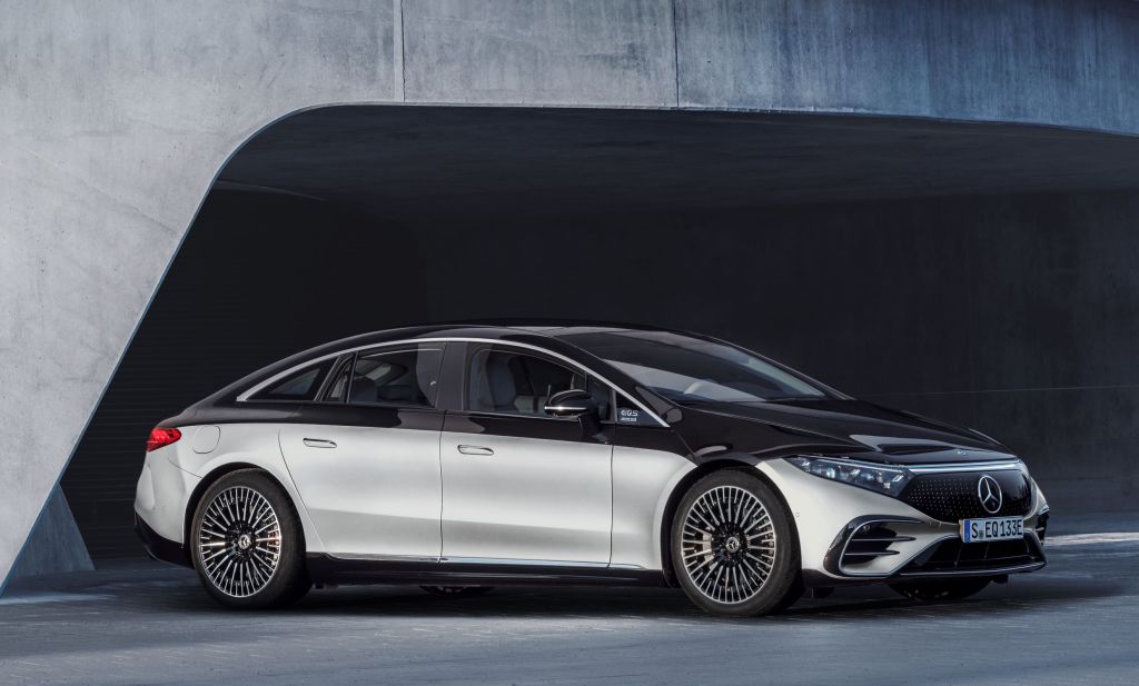 A silver-and-black 2022 Mercedes-Benz EQS electric sedan by a concrete building