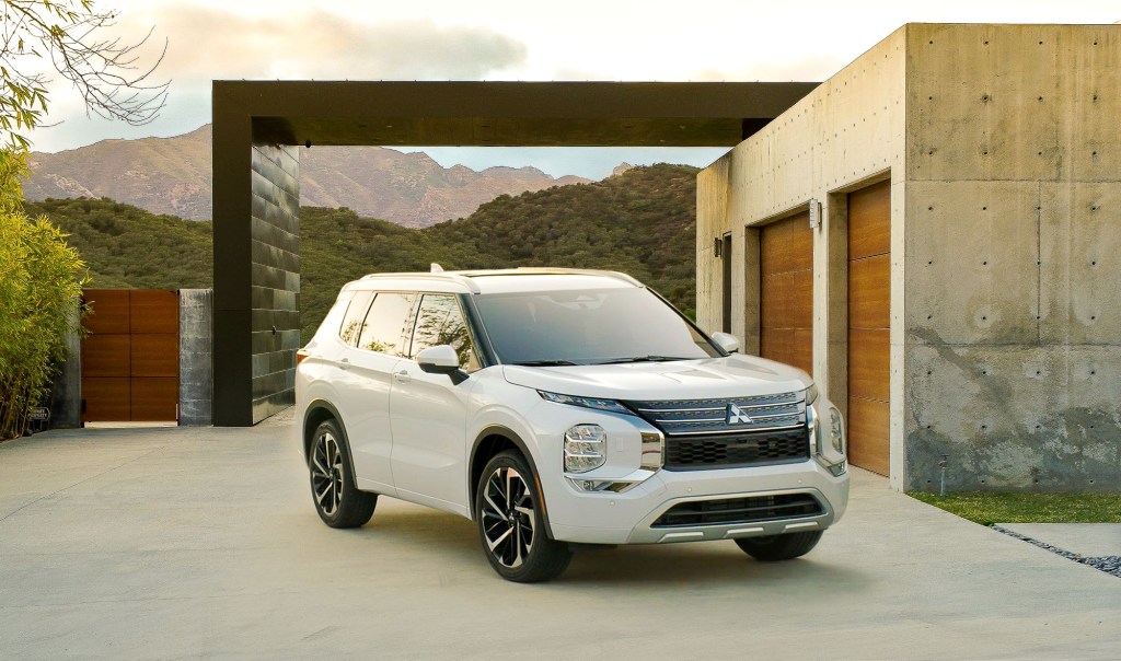 A white 2022 Mitsubishi Outlander SUV parked out of a luxury home in the mountains