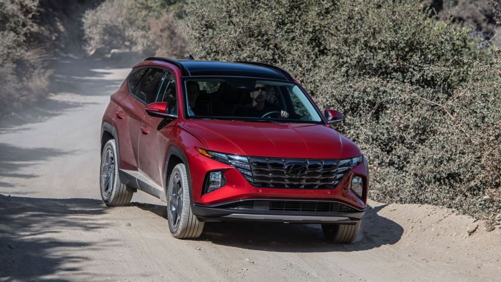 A red 2022 Hyundai Tucson driving on a dirt road