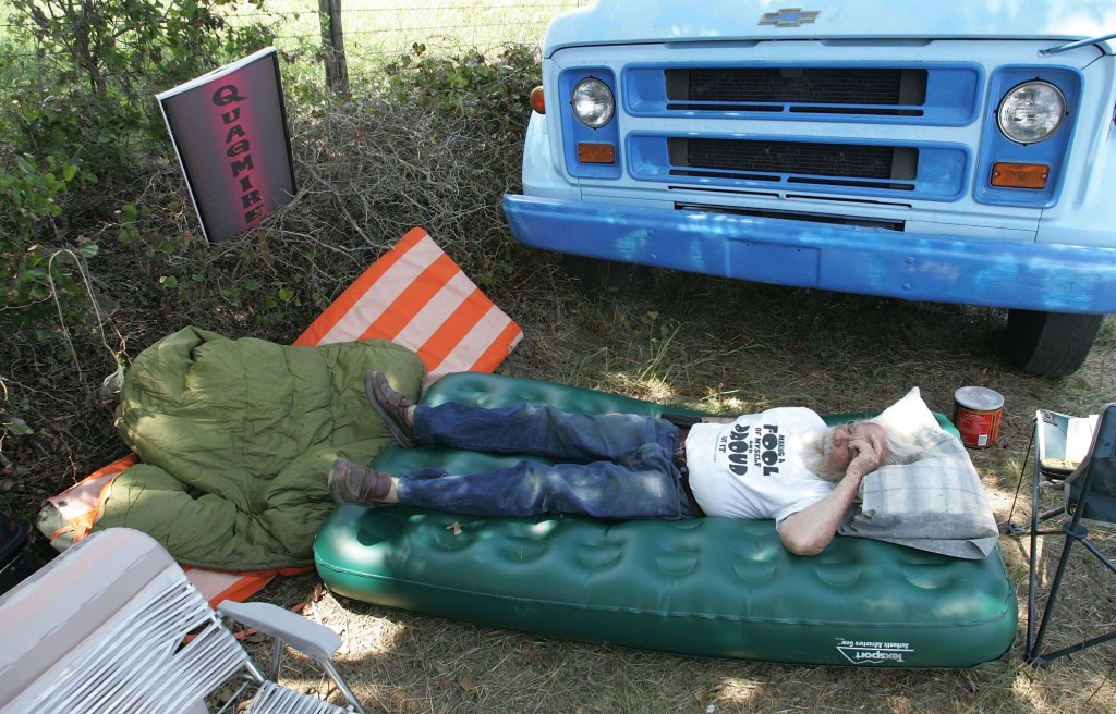 A man lying on an air mattress outside of his Chevy vehicle