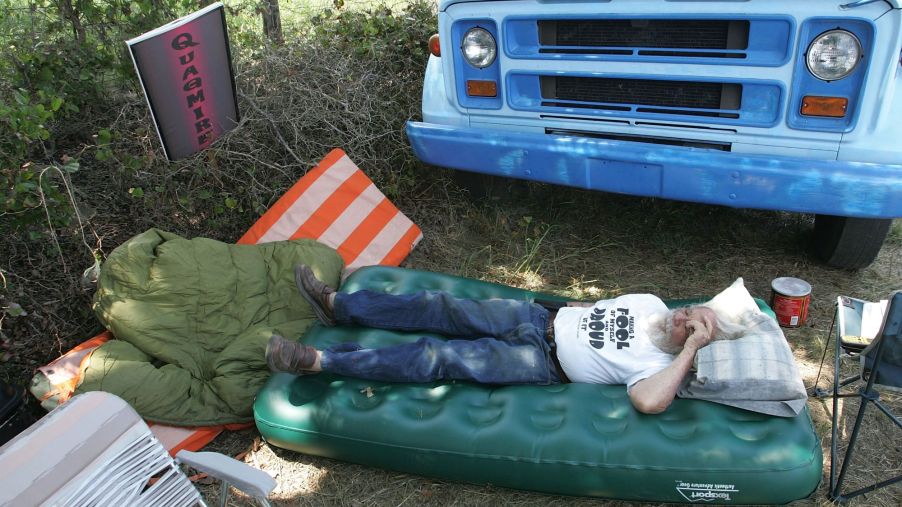 A man lying on an air mattress outside of his Chevy vehicle