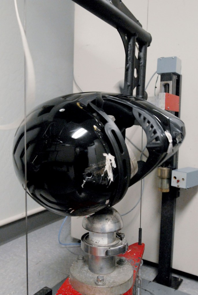 A black motorcycle helmet undergoing testing at the Snell Memorial Foundation