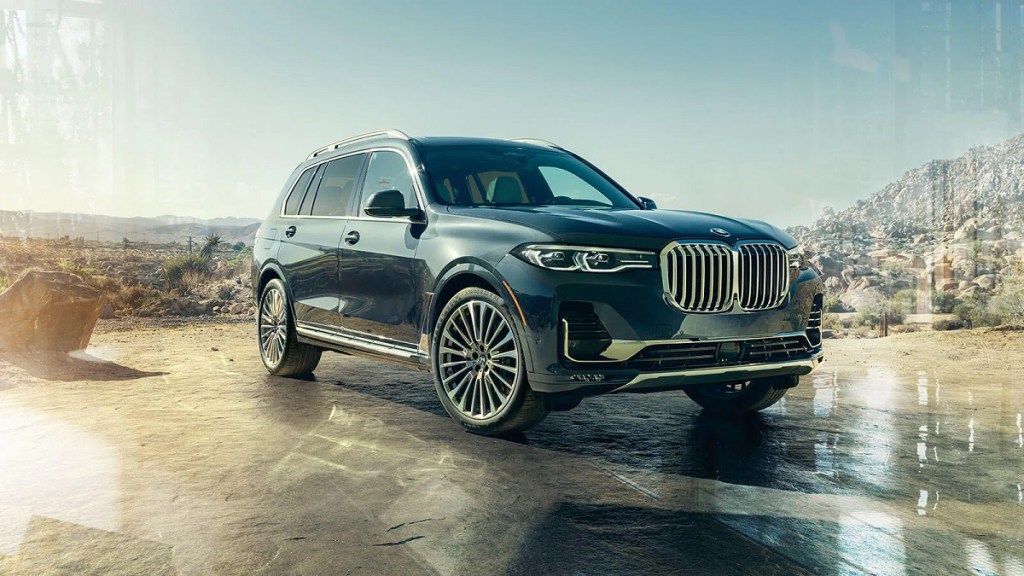 A black 2021 BMW X7 sits in a wooded clearing. 