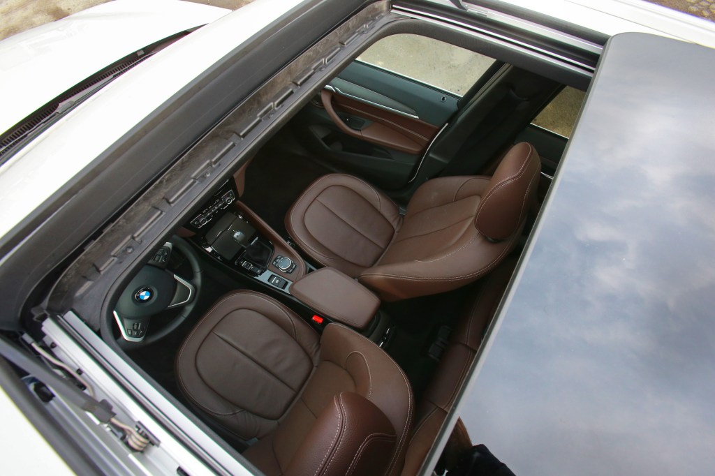 An overhead shot of a panoramic sunroof reveals the brown-leather interior of a 2016 BMW X1 xDrive 28i