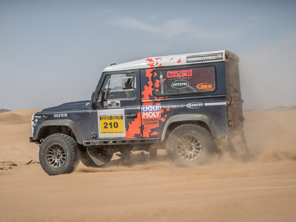 The side view of a classic Land Rover Defender converted to Challenge spec by Bowler racing in the desert