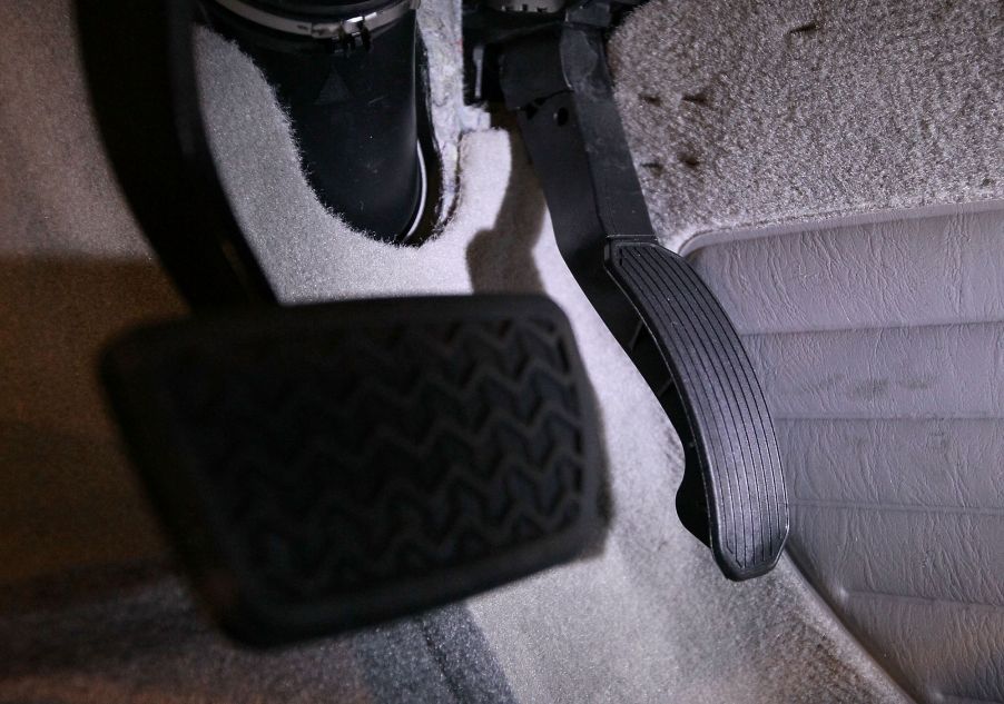 The brake and gas pedals attached to carpet upholstery under the driver's seat