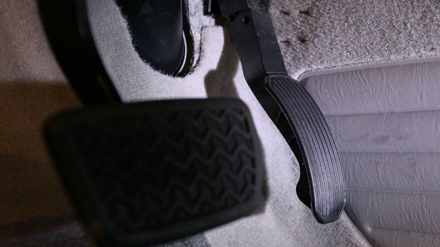 The brake and gas pedals attached to carpet upholstery under the driver's seat