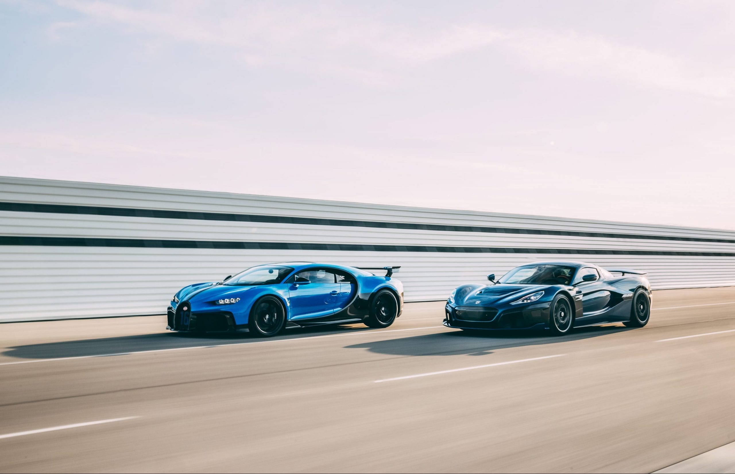 A blue-and-black Bugatti Chiron Sport and a black Rimac Nevera speed around a racetrack