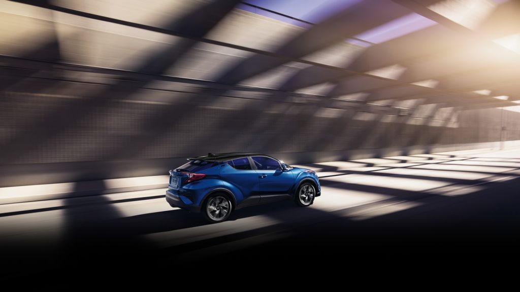 a blue 2021 Toyota CH-R driving at speed in a press photo