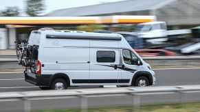 A campervan driving down the highway with a blurred background.