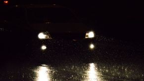 A pair of car headlights driving through darkness