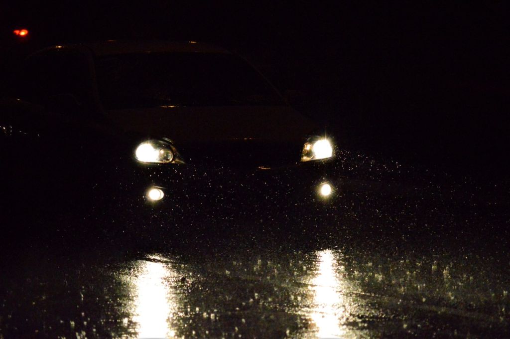 A pair of car headlights driving through darkness