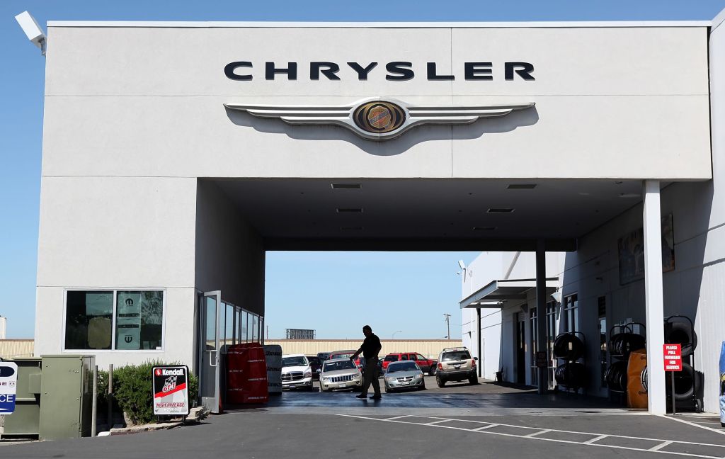 A Chrysler Service Bay with the Chrysler logo at the top and a person standing in the middle hosing off the ground.