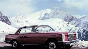 A red 1967 Mercedes 'W114' 250C coupe in the snow-covered mountains