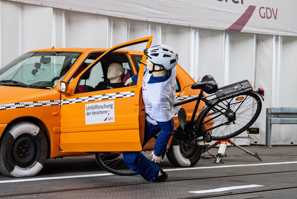 In a crash test conducted by the insurers' accident researchers, a crash test dummy on a bicycle crashes into an open door of a parked car - a so-called dooring accident