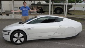 Doug DeMuro with a white 2014 Volkswagen XL1 in an industrial parking lot
