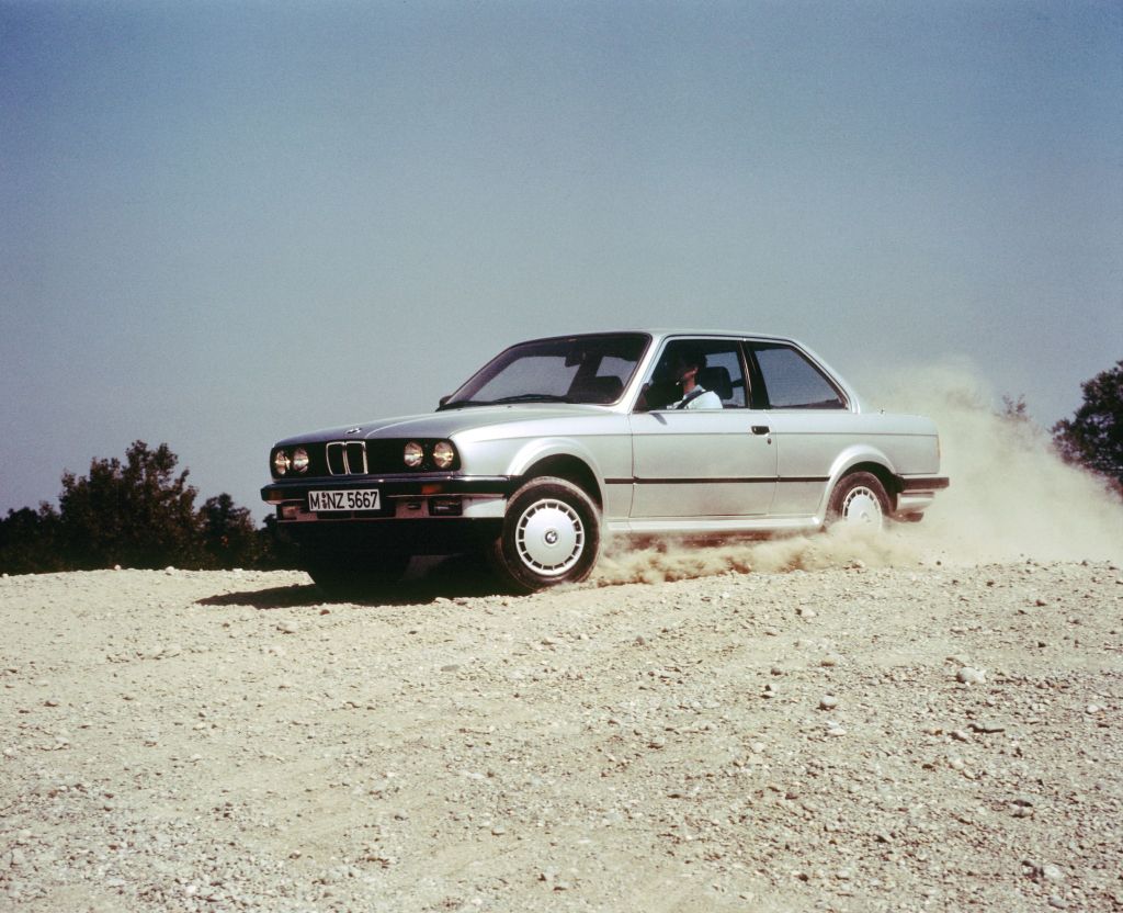 A silver E30 BMW 325iX sliding through gravel