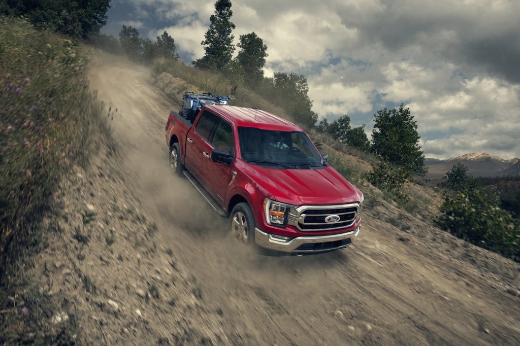 A red 2021 Ford F-150 drives down a dirt hill.