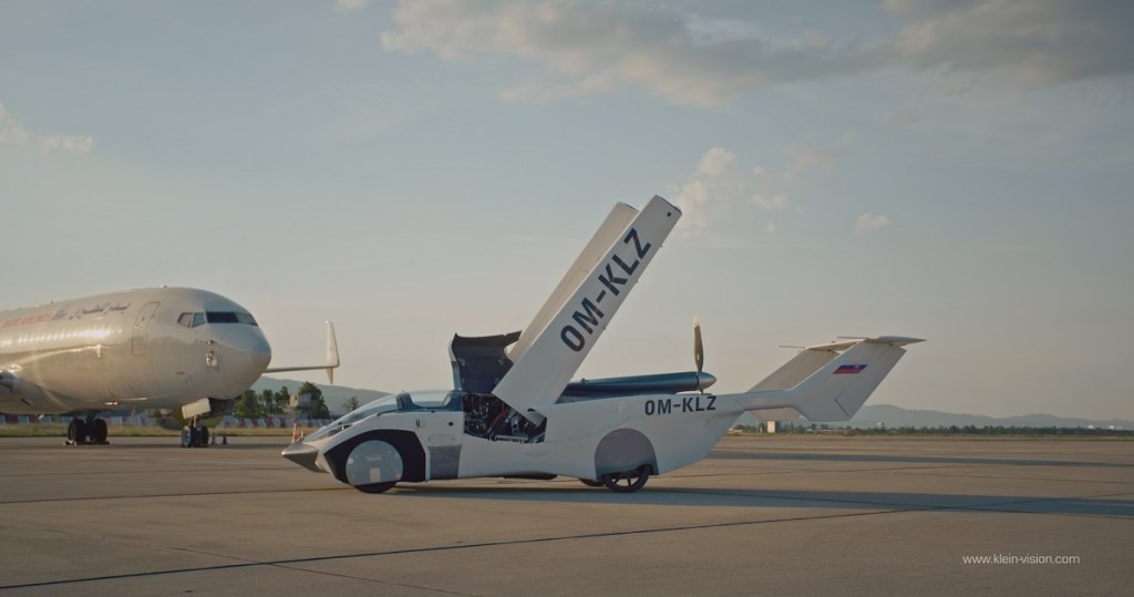 An AirCar sits on a runaway with its wings up.