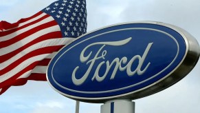 A Ford sign at a dealership next to a flying flag.