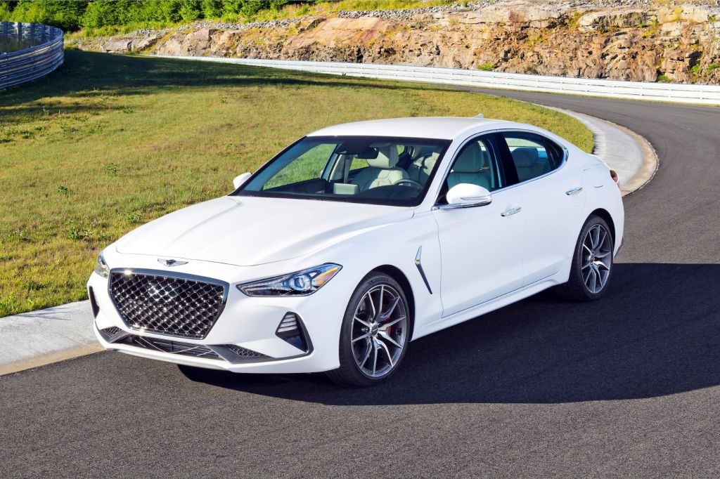 A white Genesis G70 luxury sedan model driving on a country highway