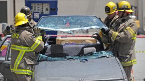 A group of firefighters cut the roof off of a crashed car