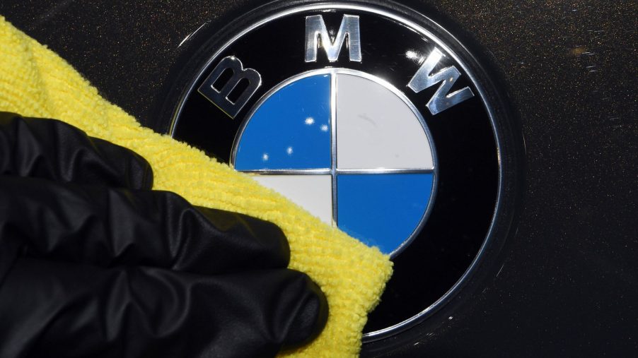A BMW employee puts down a coat of wax onto the hood of a black BMW
