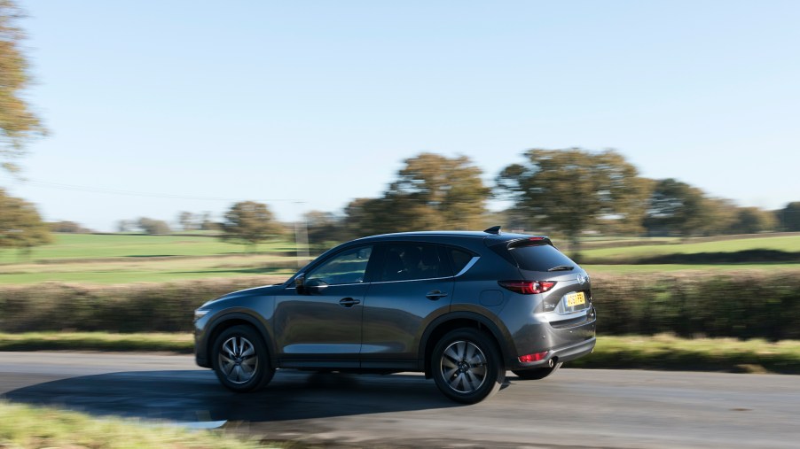 The second generation Mazda CX-5 driving at speed on a scenic country road.