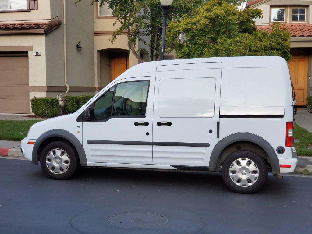 a white Ford transit Connect parked in a neighborhood