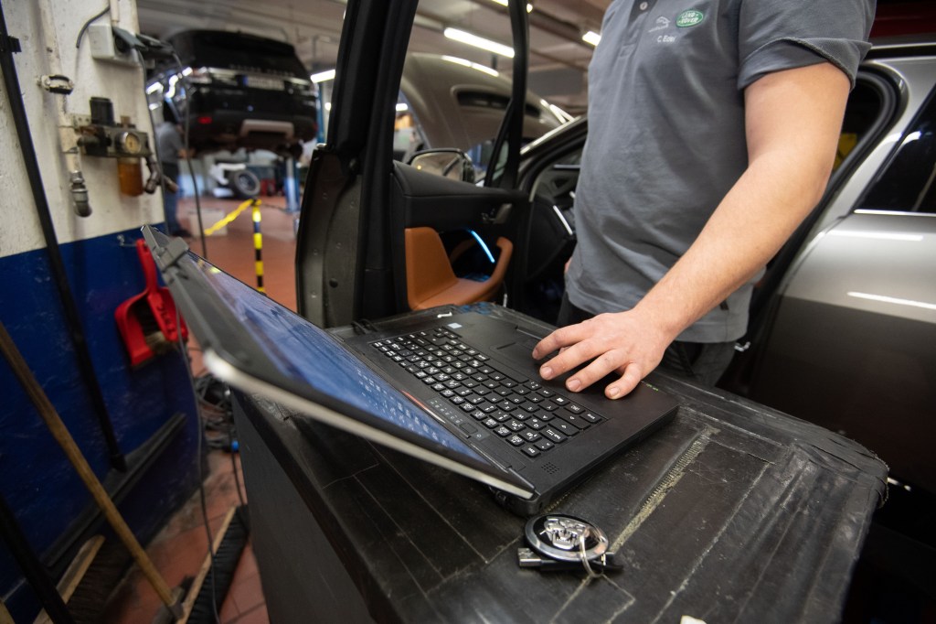 A mechanic uses a laptop to work on a Jaguar
