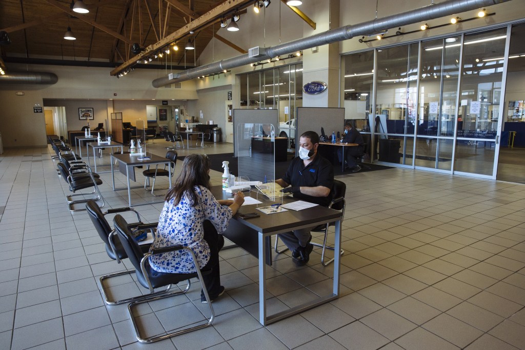 A customer begins to negotiate with a salesperson at a Ford dealership
