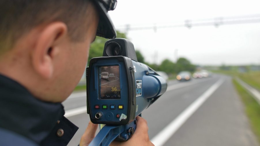 A police officer aims a radar gun at traffic looking for speeders