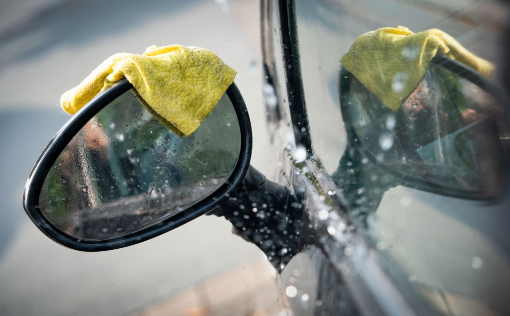  A rag lies on the rear-view mirror of a car during a car wash.