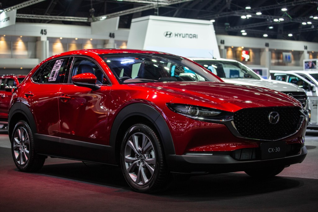 a red 2021 Mazda CX-30 on display at an indoor auto show, front quarter view 