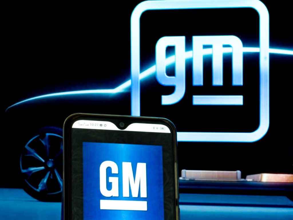 The old and new GM logos illuminated against a black backdrop
