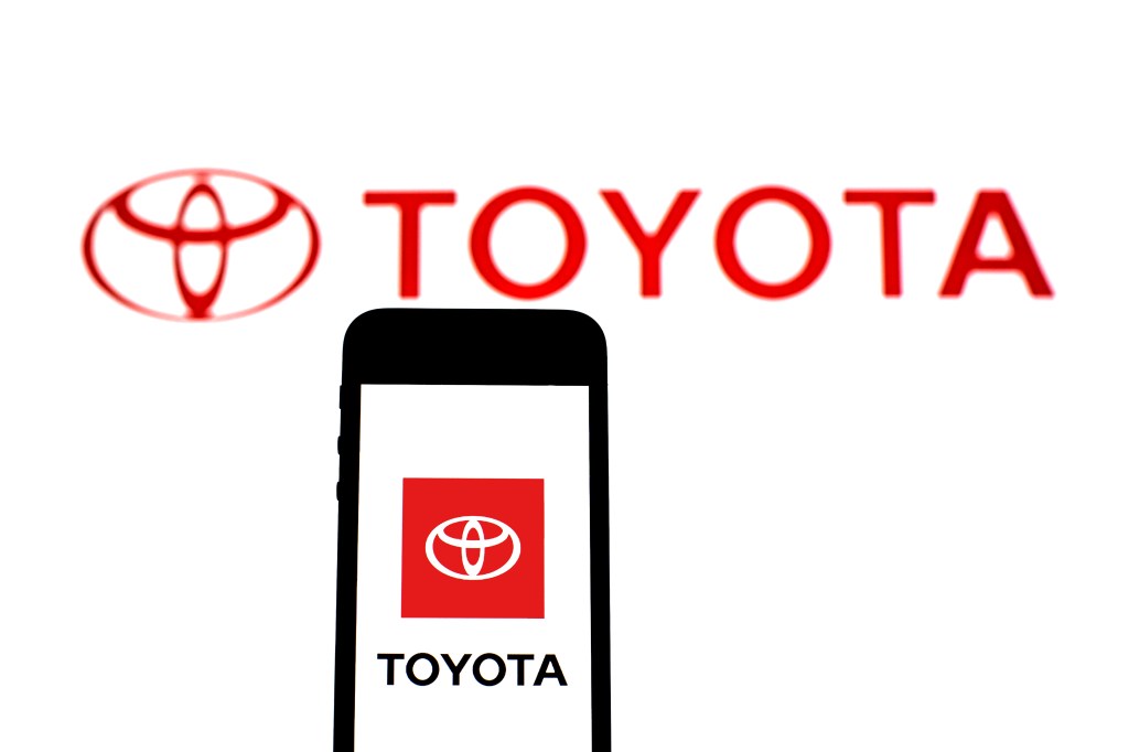 Toyota Motor Corporation logo on a white screen with a phone that also has the logo pulled up  