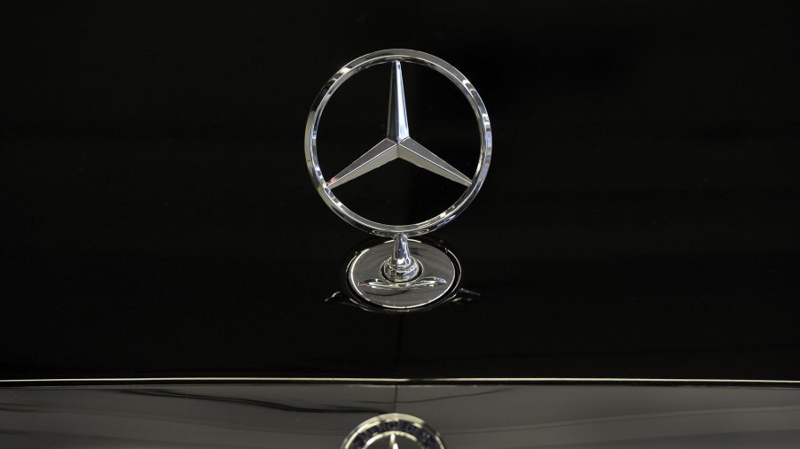 The Mercedes-Benz badge affixed to the hood of a black S Class sedan